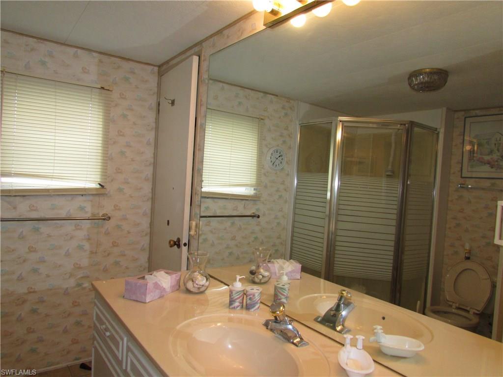 113 Enchanting Boulevard, Unit E113 Naples, FL 34112 - Photo 7 of 11 a bathroom with a granite countertop sink toilet and shower