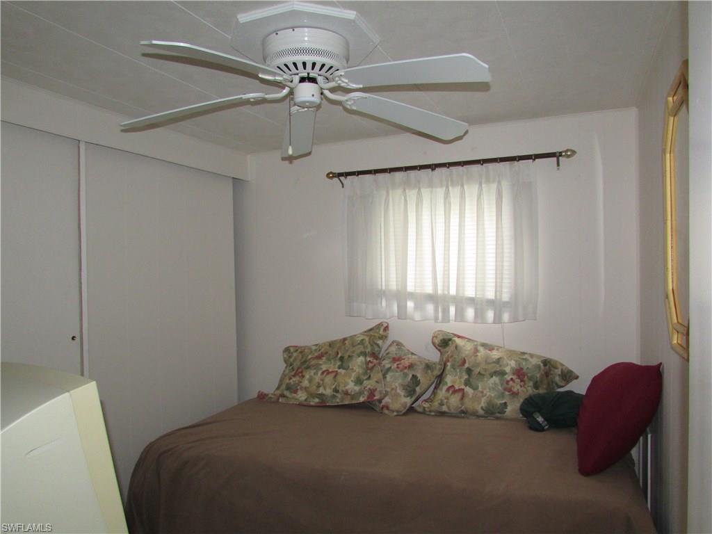 113 Enchanting Boulevard, Unit E113 Naples, FL 34112 - Photo 8 of 11 a bed room with a bed and a chandelier