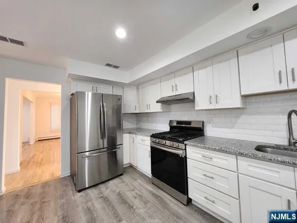 a kitchen with cabinets stainless steel appliances and wooden floor