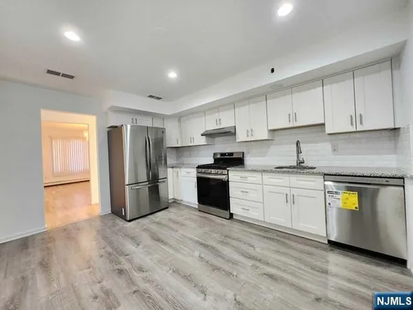 a kitchen with a refrigerator a stove top oven a sink and cabinets