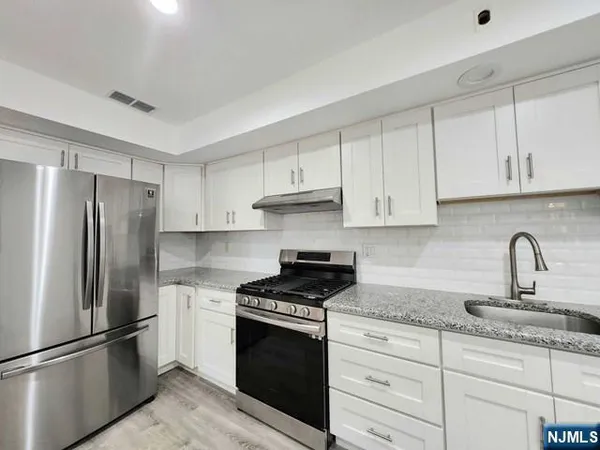 a kitchen with granite countertop white cabinets and stainless steel appliances