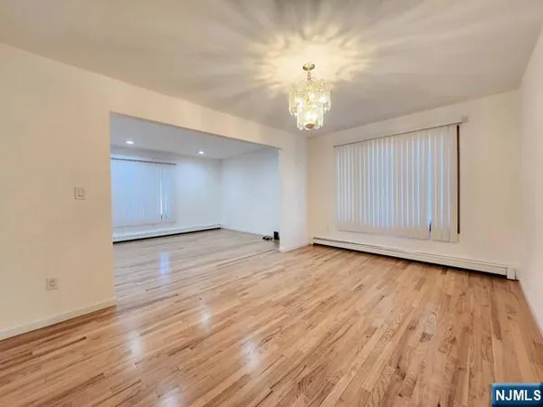 an empty room with wooden floor and chandelier