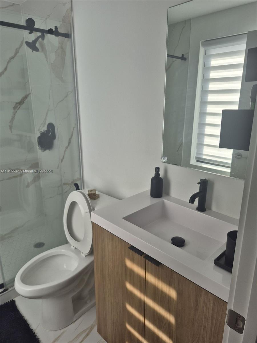 14515 Southwest 261st Street, Unit 14515 Homestead, FL 33032 - Photo 4 of 13 a bathroom with a sink a toilet and a mirror