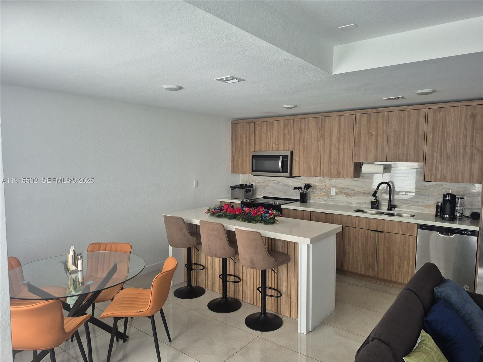 14515 Southwest 261st Street, Unit 14515 Homestead, FL 33032 - Photo 7 of 13 a kitchen with a sink a stove a refrigerator cabinets and chairs