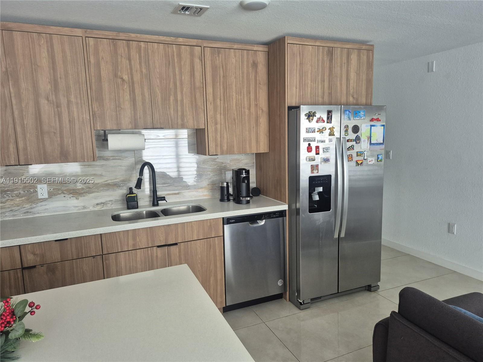 14515 Southwest 261st Street, Unit 14515 Homestead, FL 33032 - Photo 8 of 13 a kitchen with stainless steel appliances a refrigerator sink and cabinets