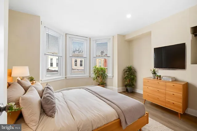 a bedroom with a bed and a flat tv screen on dresser