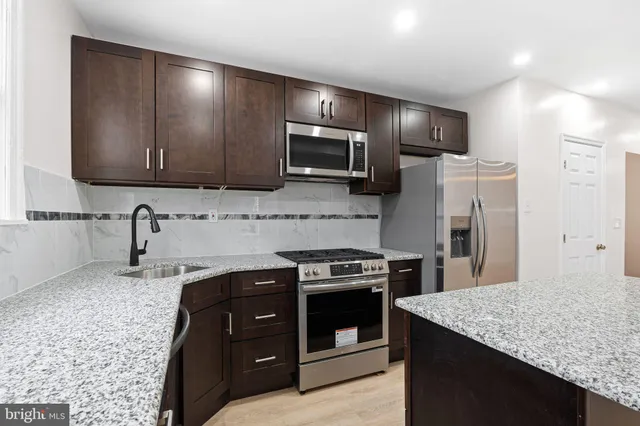 a kitchen with a sink a stove top oven and refrigerator