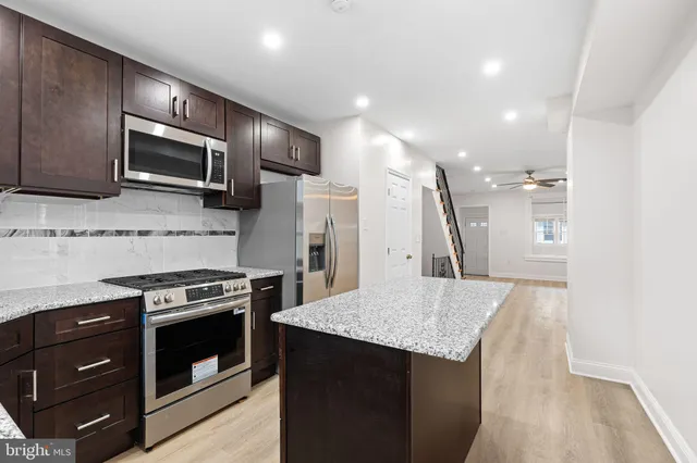 a kitchen with stainless steel appliances kitchen island granite countertop a stove a refrigerator and a microwave