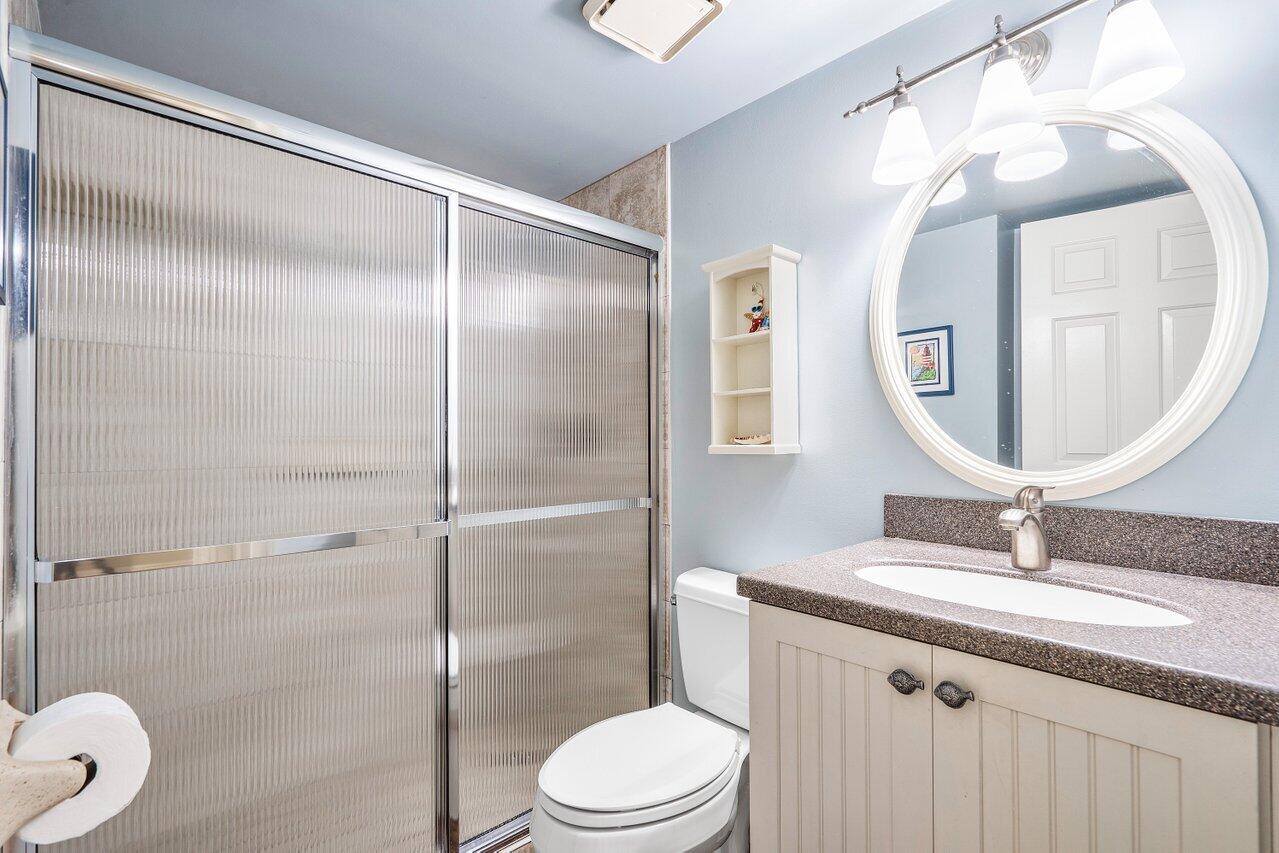 275 Palm Avenue, Unit C206 Jupiter, FL 33477 - Photo 19 of 25 a bathroom with a toilet a sink and mirror
