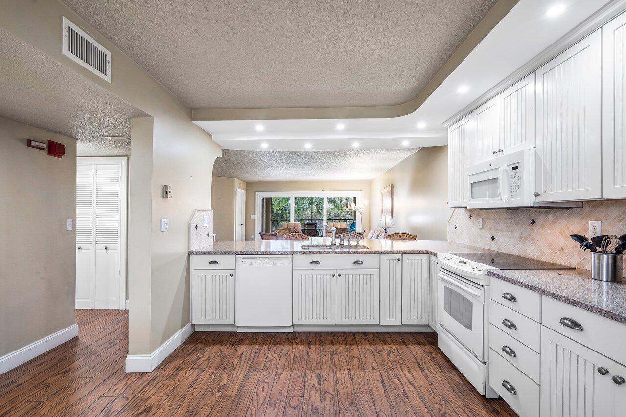 275 Palm Avenue, Unit C206 Jupiter, FL 33477 - Photo 7 of 25 a kitchen with sink cabinets and wooden floor