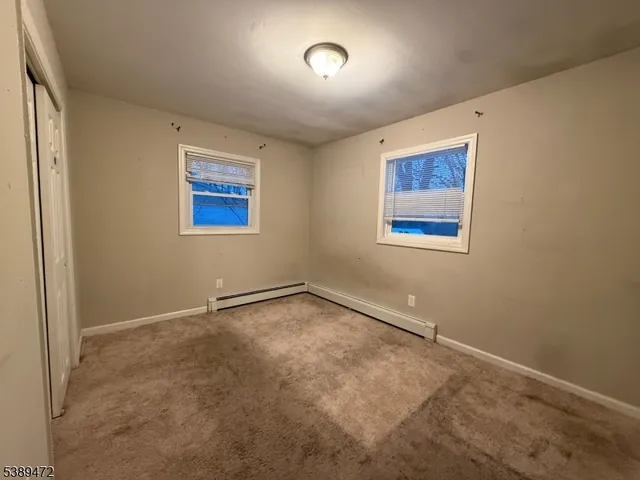 an empty room with a painting and a window