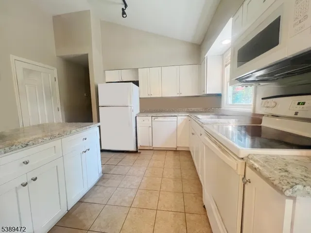 a kitchen with granite countertop cabinets sink and white appliances