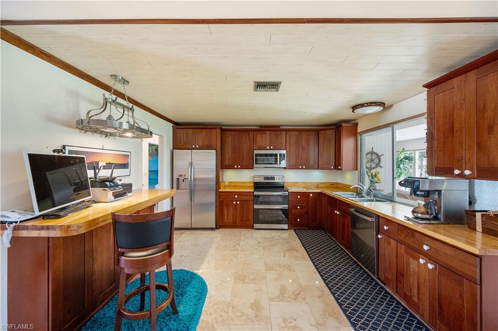 397 Forest Hills Boulevard Naples, FL 34113 - Photo 13 of 29 Stainless steel appliances with cherry wood cabinets.