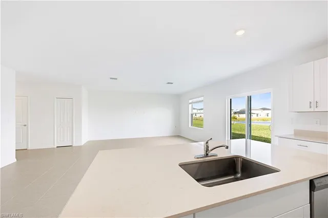 a kitchen with granite countertop white cabinets sink and stainless steel appliances