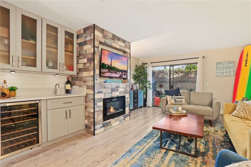 Great shot of the size of the Living space with modernized Wet Bar/Wine Cooler and Reclaimed wood Electric fireplace that leads to your back patio area.