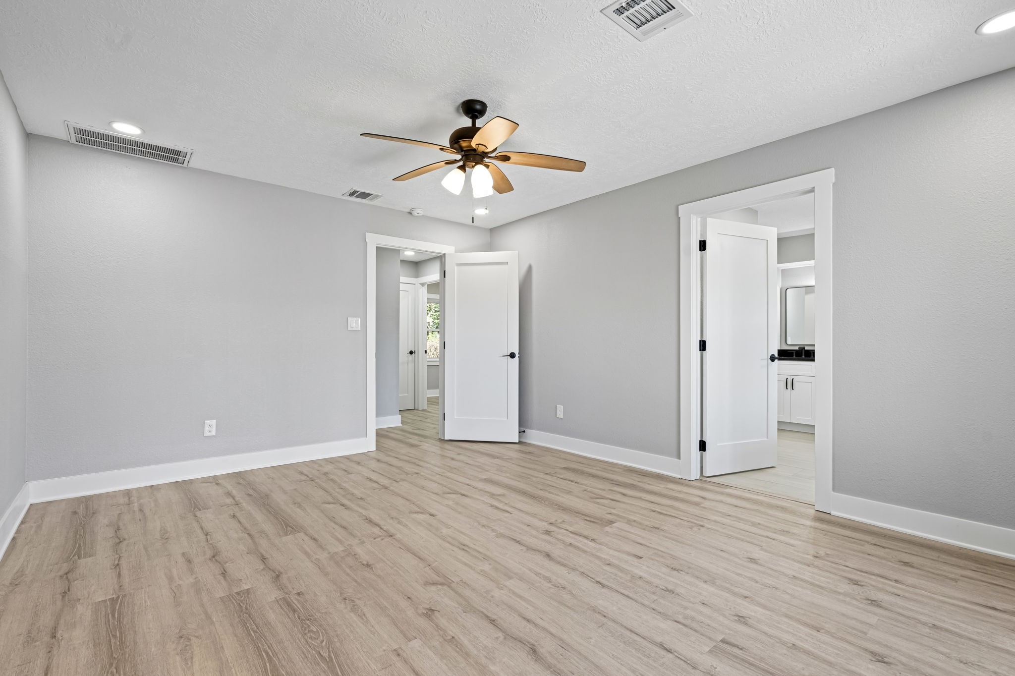 284 Hackberry Street Trinity, TX 75862 - Photo 12 of 42 The primary suite is down the stairs, is complete with luxury vinyl plank flooring, new ceiling fan, updated doors and moldings, and is complete with a spacious en-suite bathroom.