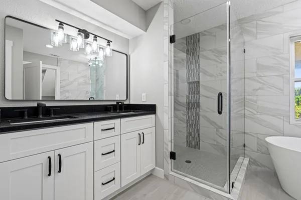 a bathroom with a granite countertop sink a mirror and shower