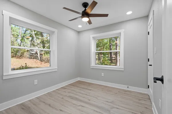 a view of an empty room with wooden floor and a window