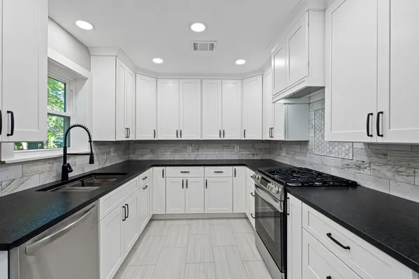 a kitchen with granite countertop a sink a stove and cabinets