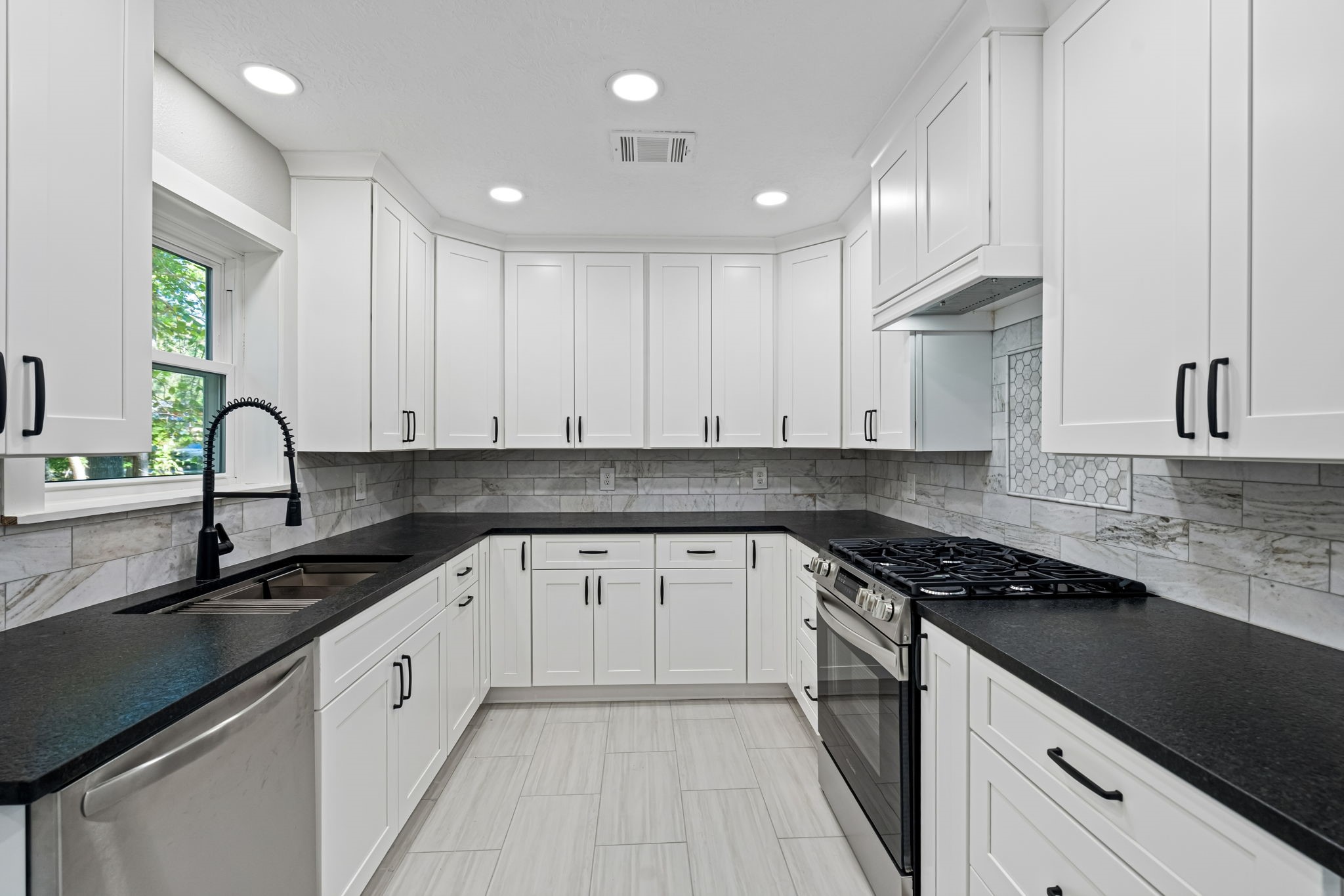 284 Hackberry Street Trinity, TX 75862 - Photo 6 of 42 Concealed ventilation, a mosaic tile insert, slide-in range and black hardware complete the space.