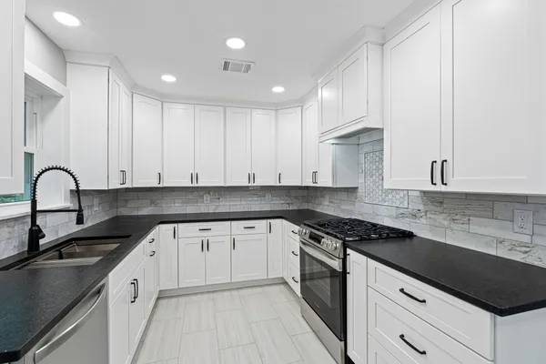 a kitchen with granite countertop white cabinets and appliances