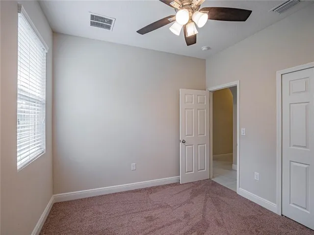 an empty room with a window and a fan