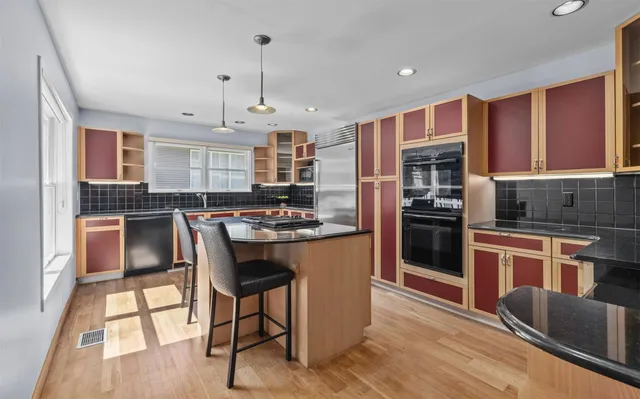 a kitchen with stainless steel appliances kitchen island granite countertop a sink stove and refrigerator