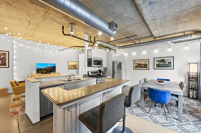 a dining hall with stainless steel appliances granite countertop a sink a stove and chairs with wooden floor