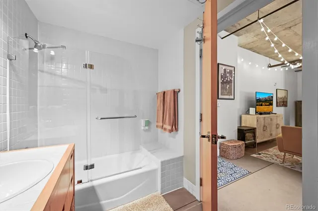 a bathroom with a tub a mirror and a shower