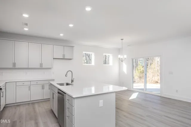 a kitchen with a sink a stove a refrigerator and white cabinets