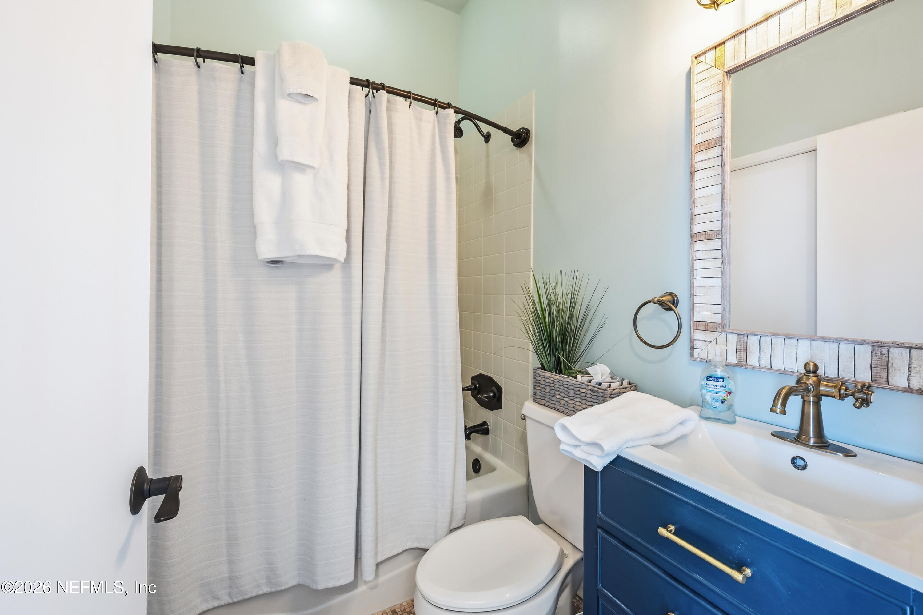 75 Comares Avenue, Unit 3A St. Augustine, FL 32080 - Photo 26 of 41 a bathroom with a sink a toilet a mirror and shower curtain