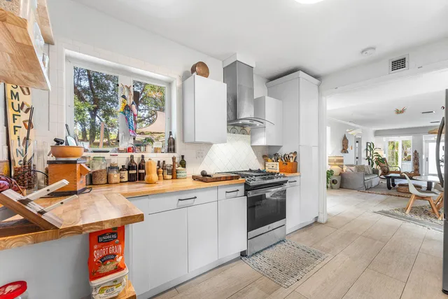 a large white kitchen with stainless steel appliances granite countertop a stove and a sink