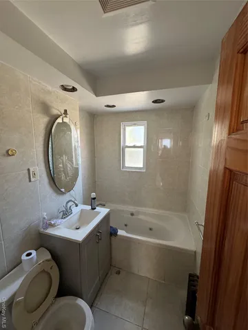 a bathroom with a bathtub sink mirror and toilet