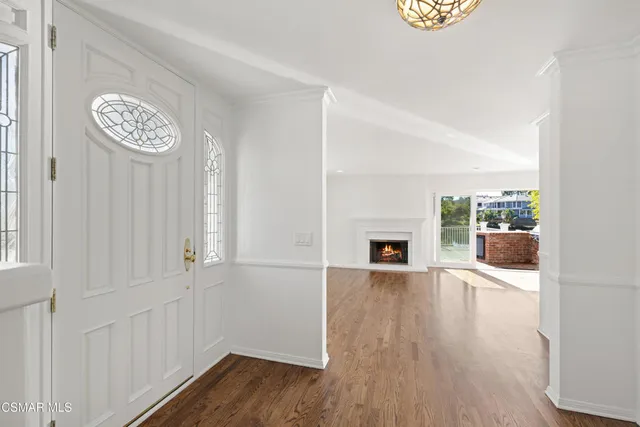 an empty room with wooden floor fireplace and windows