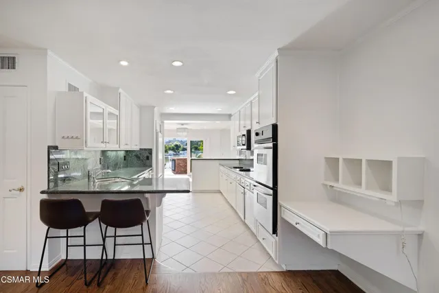 a kitchen with stainless steel appliances kitchen island granite countertop a refrigerator and a cabinets