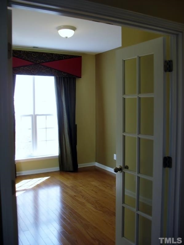 5328 Shaker Heights Lane Raleigh, NC 27613 - Photo 18 of 25 a view of an empty room with wooden floor and a window