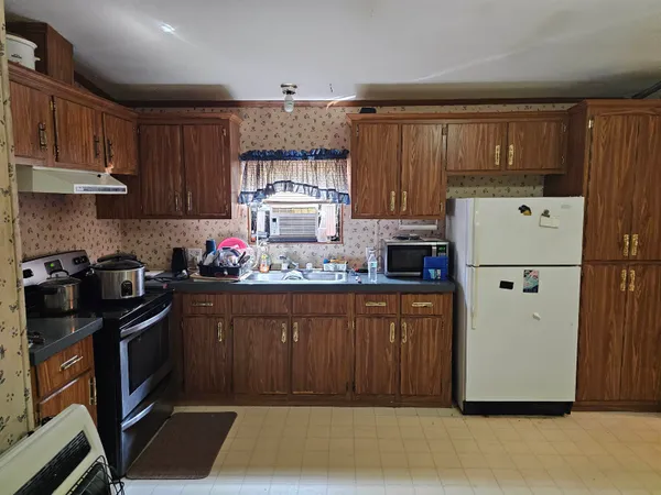 a kitchen with granite countertop a refrigerator stove and wooden cabinets