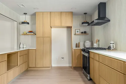 a kitchen with stainless steel appliances a refrigerator a sink and wooden floors