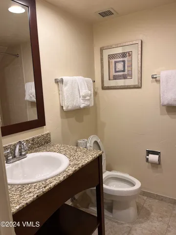 a bathroom with a granite countertop toilet sink and mirror