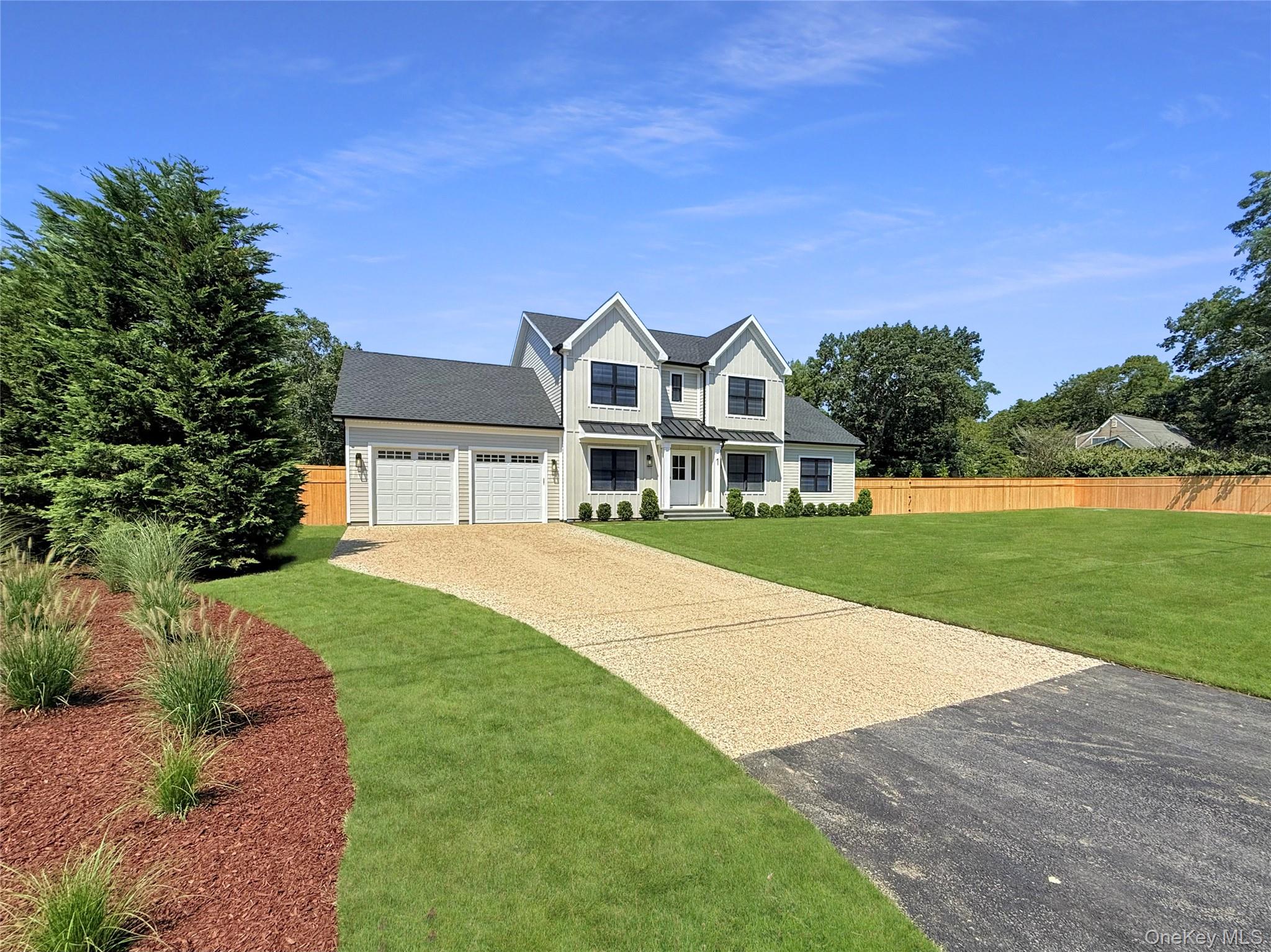 Modern farmhouse with board and batten siding, driveway, an attached garage, roof with shingles, and a standing seam roof