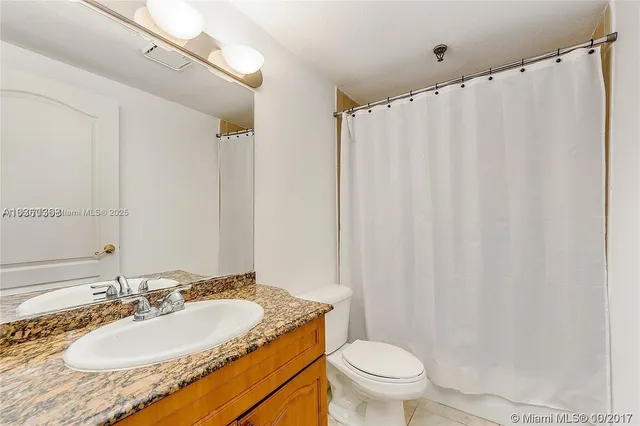 a bathroom with a granite countertop sink toilet and a mirror