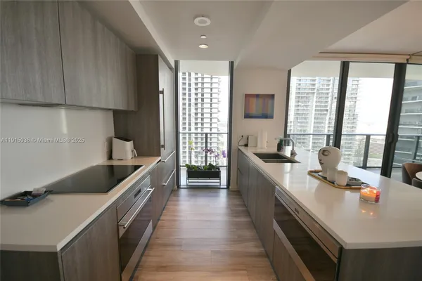 a kitchen with counter top space a sink wooden floor and cabinets
