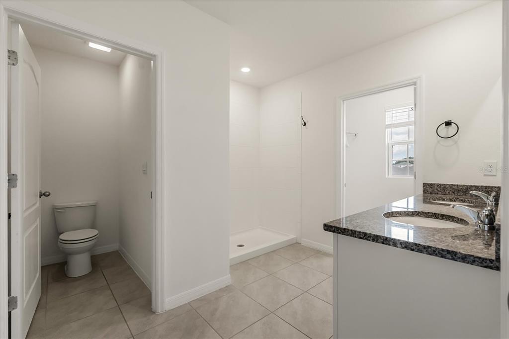 6814 Grace Hammock Road Harmony, FL 34773 - Photo 25 of 41 a bathroom with a granite countertop sink a toilet and a mirror