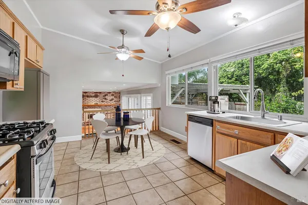 a kitchen with stainless steel appliances granite countertop a stove a sink dishwasher and a dining table with wooden floor