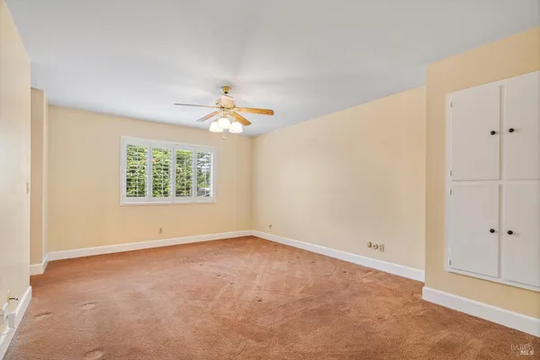 an empty room with windows and chandelier fan