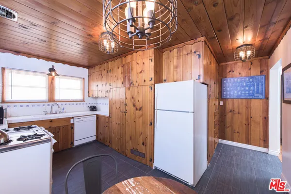 a kitchen with stainless steel appliances granite countertop a refrigerator a stove a sink dishwasher and a dining table with wooden floor