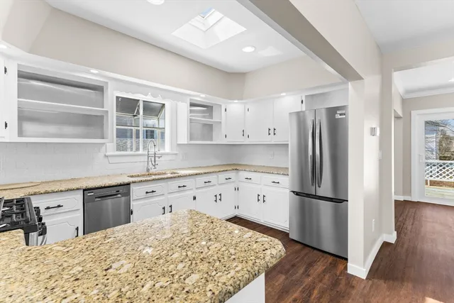 a kitchen with granite countertop a refrigerator and a stove top oven