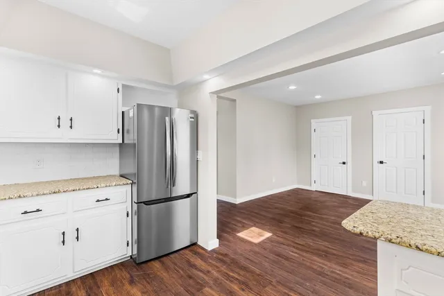 a kitchen with a refrigerator and white cabinets
