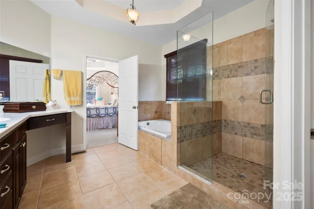 a bathroom with a tub sink vanity granite and shower