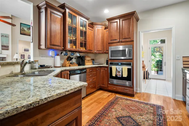 a kitchen with stainless steel appliances granite countertop a refrigerator a stove and a sink with wooden cabinets